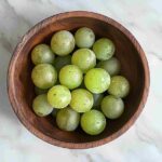 Rustic bowl of fresh, sour green grapes with dew drops.