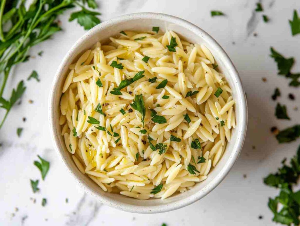 Raw orzo pasta grains on a white marble counter