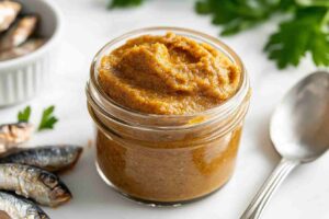 A small jar of fish paste and a spoon on white kitchen marble.