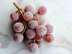 Close-up of sour frozen grapes on white marble
